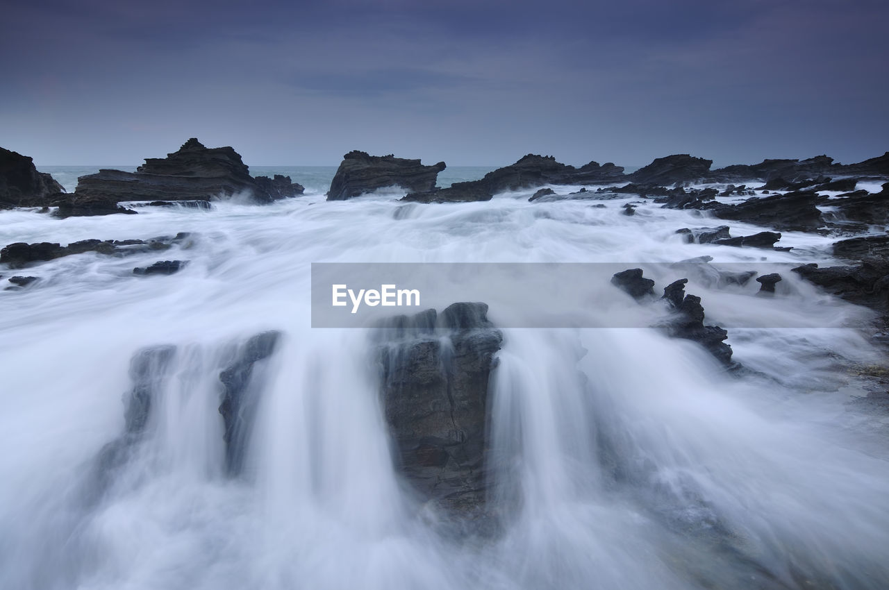 Scenic view of waterfall against sky