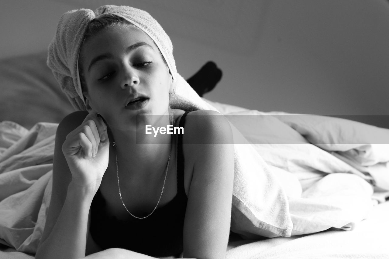 Portrait of young woman sitting on bed at home