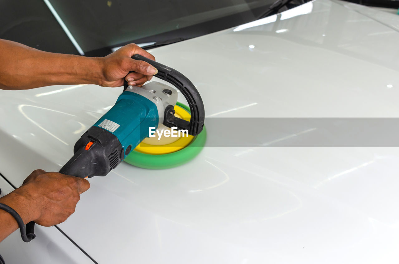 Close-up of mechanic polishing car in garage