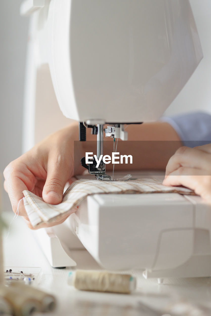 Cropped hands of tailor using sewing machine