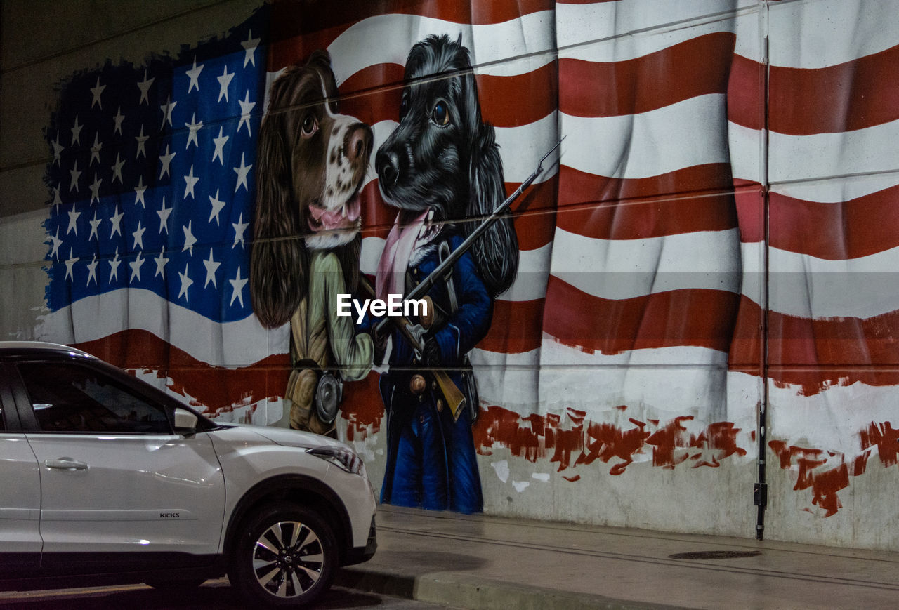 GRAFFITI ON WALL WITH UMBRELLA STANDING IN A CAR