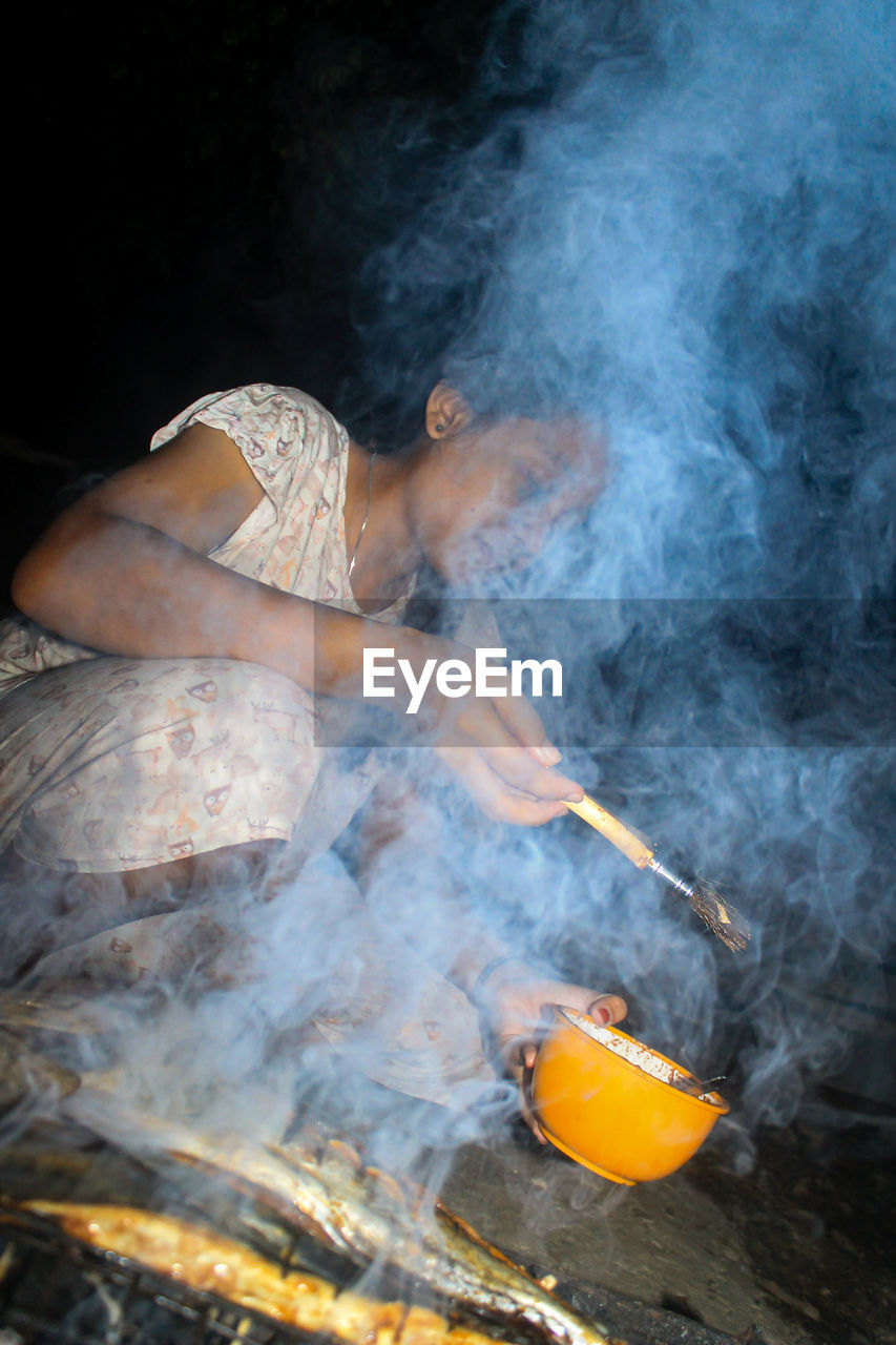 Woman preparing food on grill in darkroom