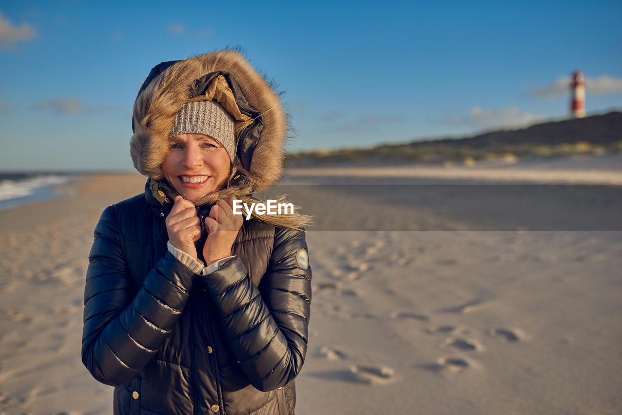 Portrait of smiling young woman standing on beach