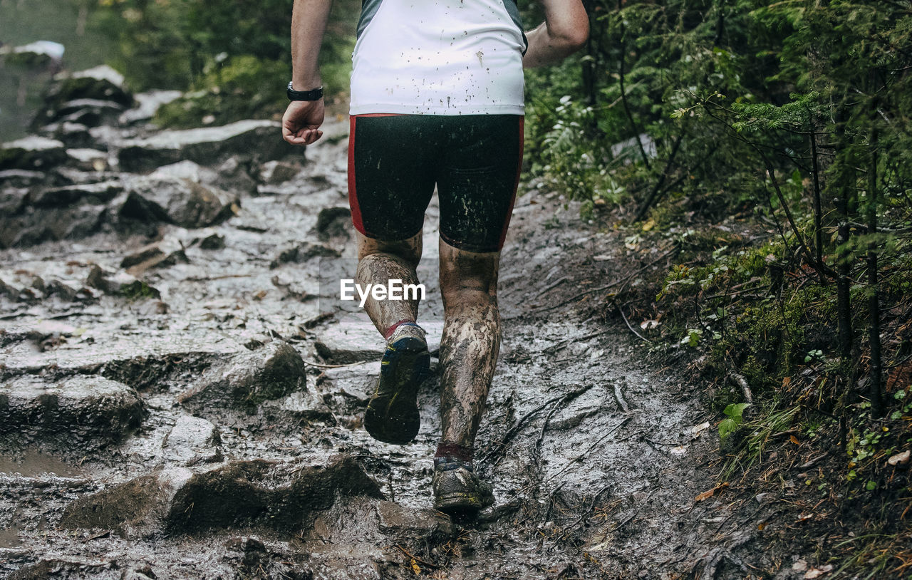 Back man runner run autumn mountain trail through mud and water