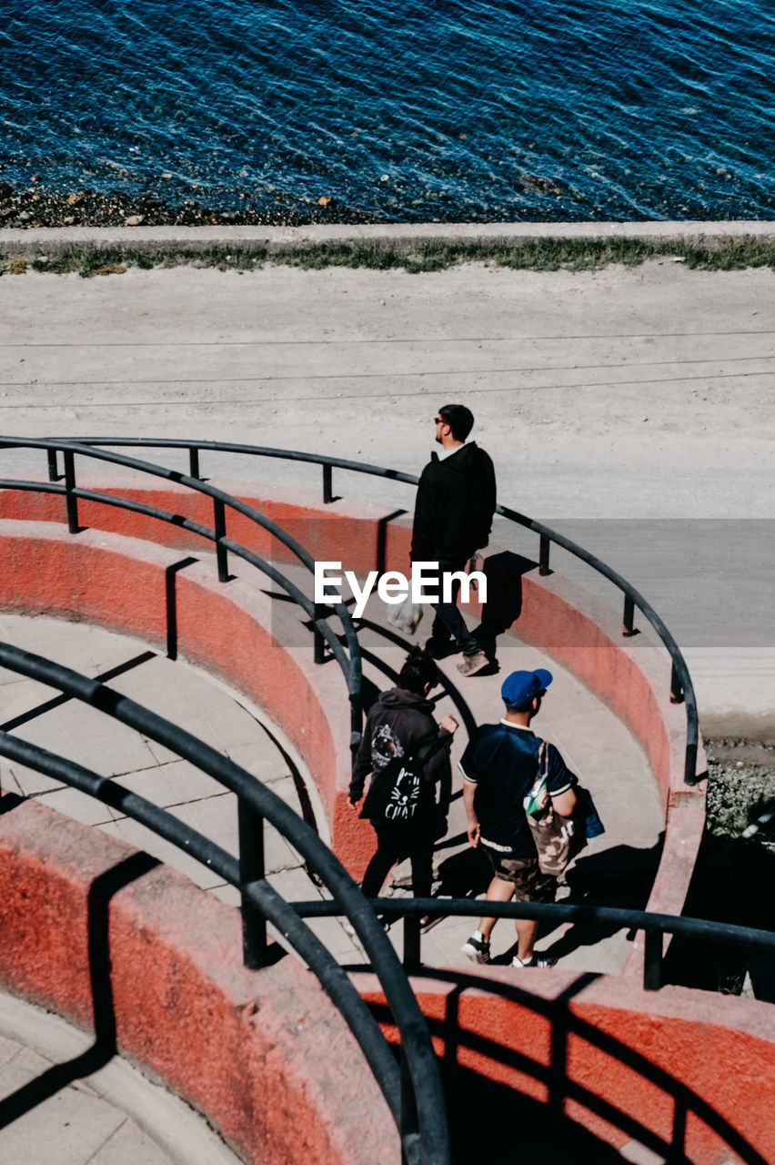 HIGH ANGLE VIEW OF MEN STANDING ON RAILING