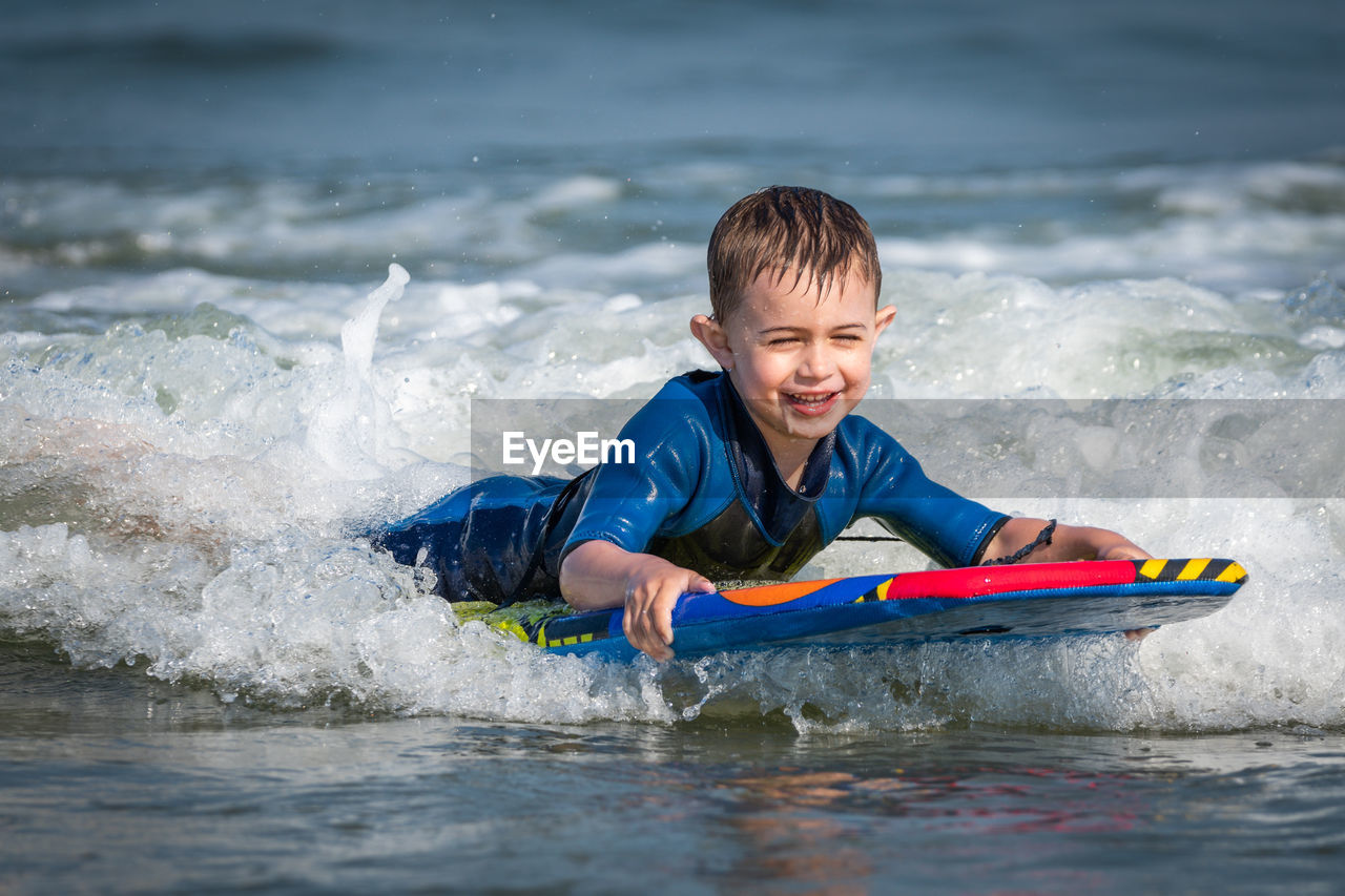 Portrait of boy swimming in sea on kneeboard