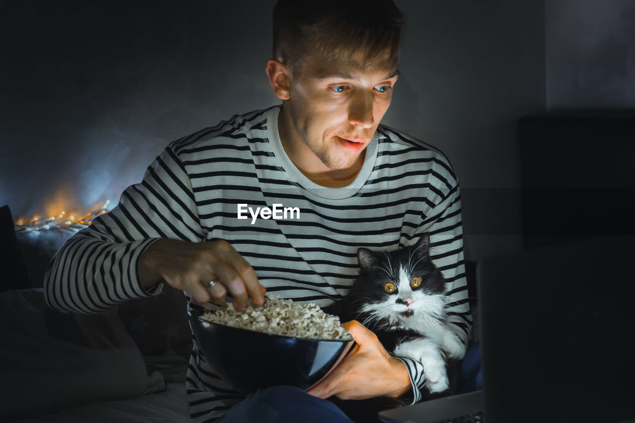 PORTRAIT OF YOUNG WOMAN WITH CAT SITTING ON FLOOR