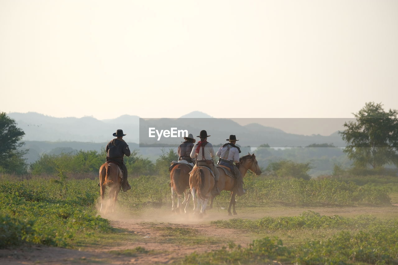 GROUP OF PEOPLE RIDING HORSE IN THE LANDSCAPE