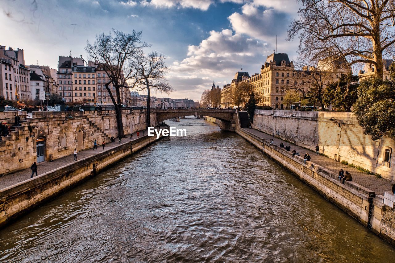 Bridge over river amidst buildings in city against sky