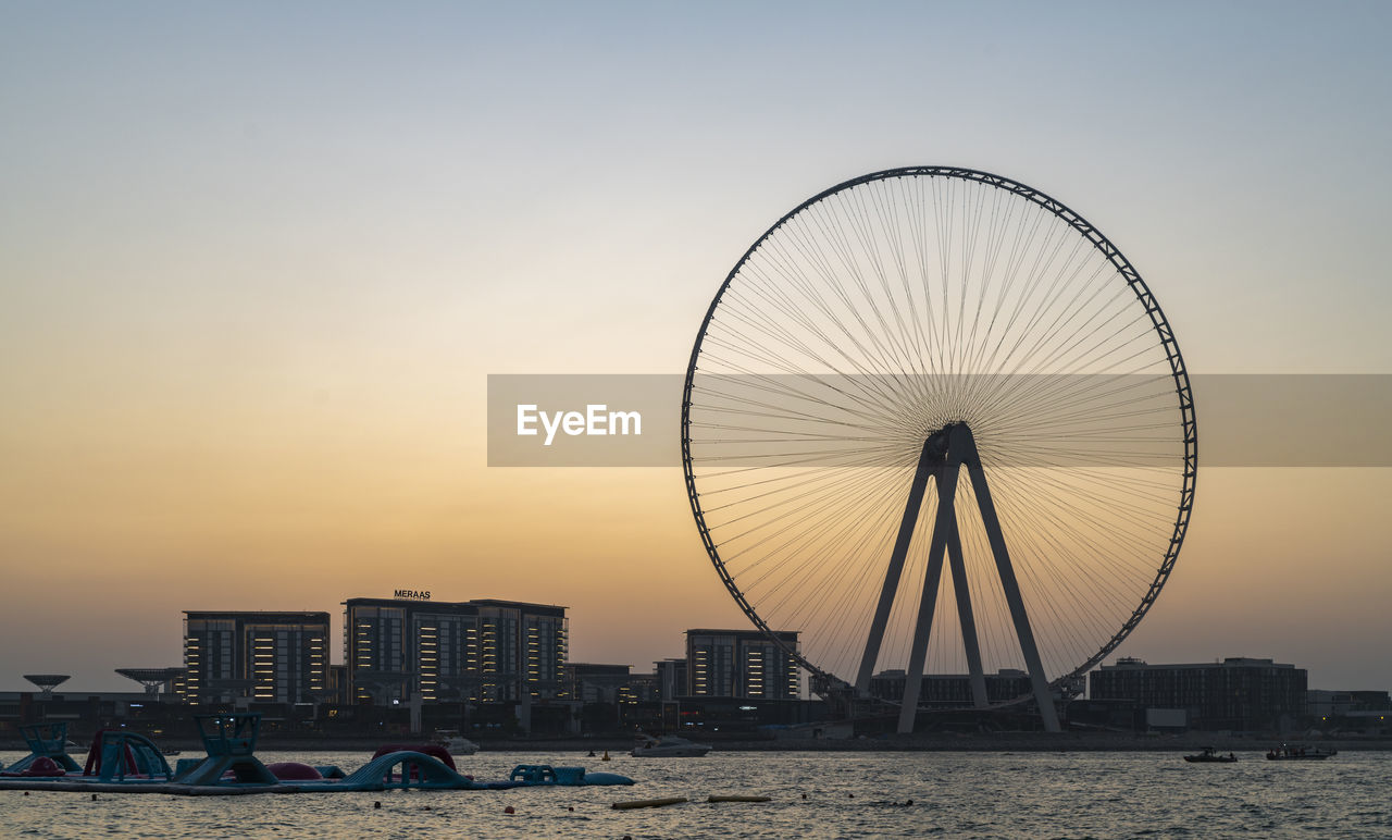 FERRIS WHEEL ON BEACH AGAINST BUILDINGS