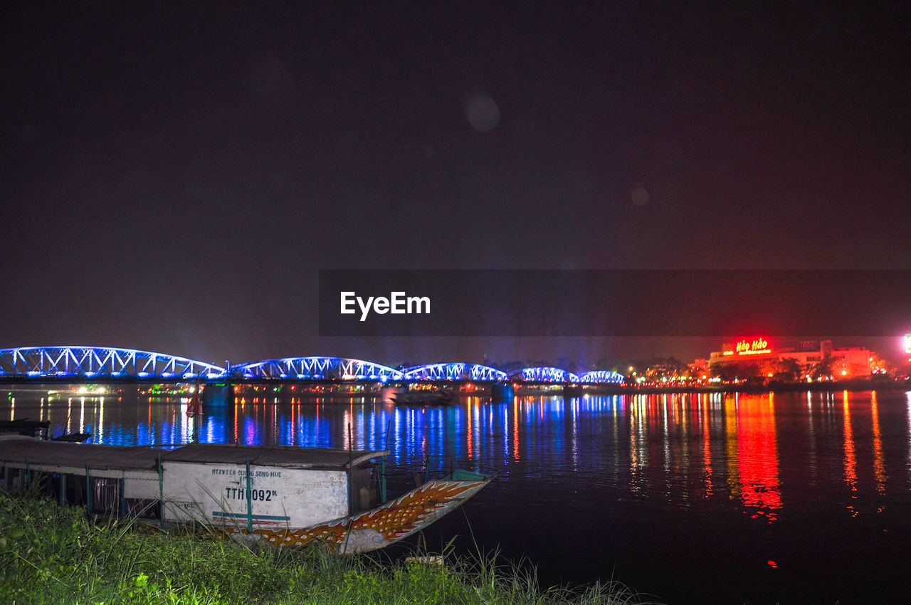 ILLUMINATED BOATS IN SEA AGAINST SKY AT NIGHT