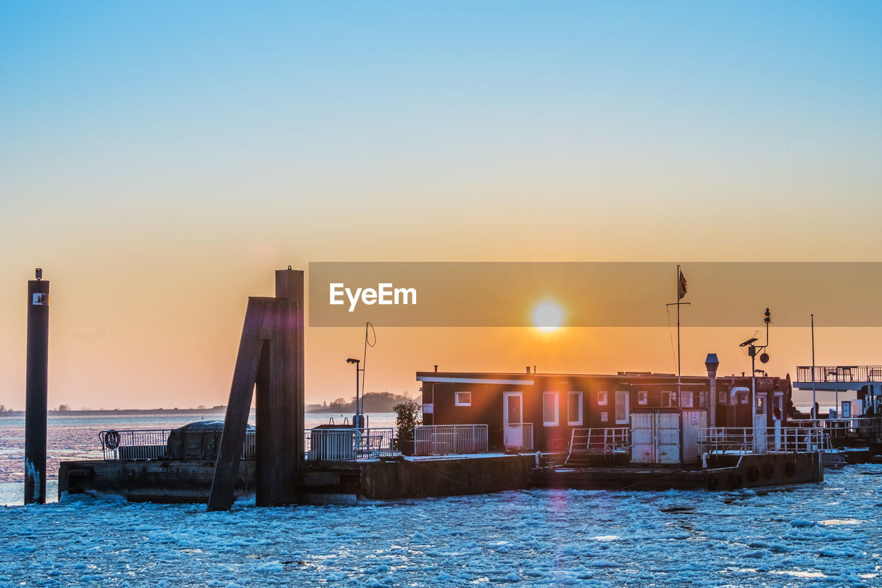 Boats moored at harbor during sunset