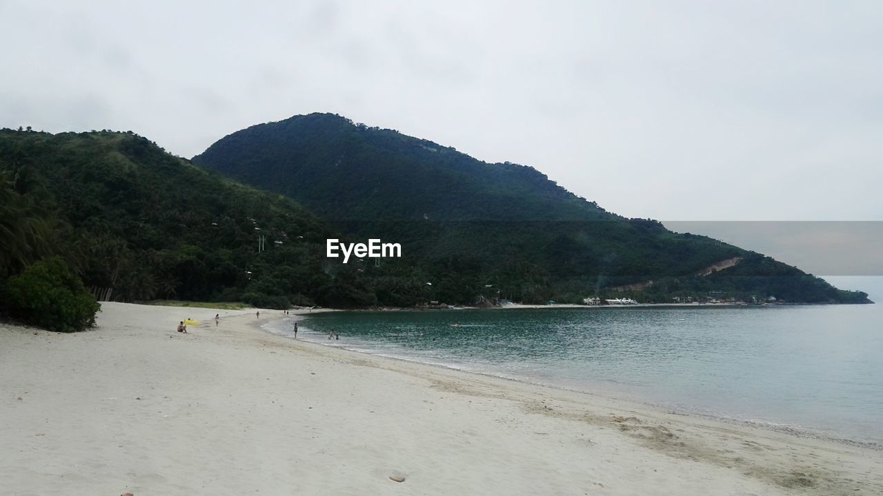 SCENIC VIEW OF BEACH BY MOUNTAIN AGAINST SKY