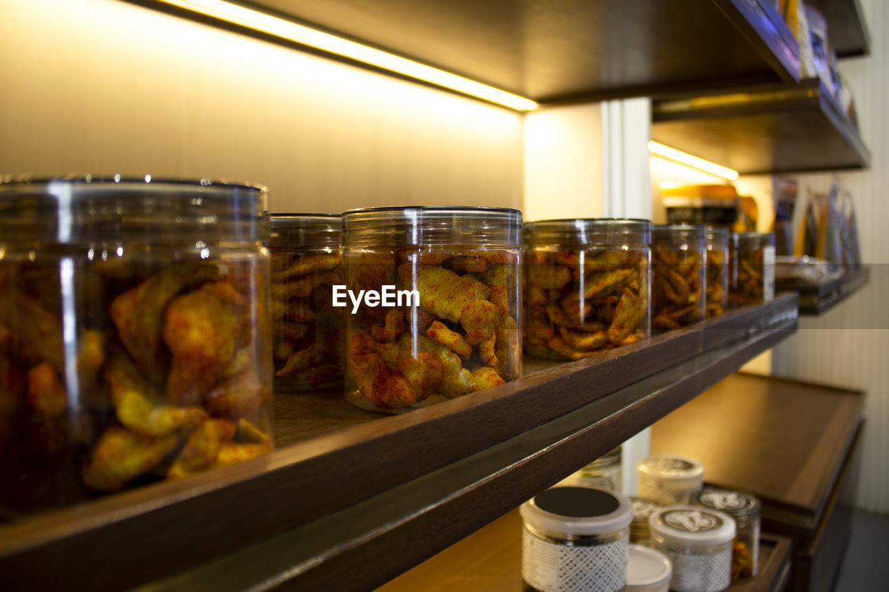 Spicy dry fruit cashew nuts packed in glass bottle arranged in racks in shop