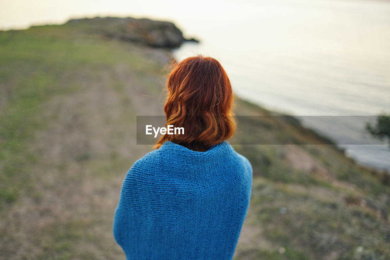 REAR VIEW OF WOMAN LOOKING AT SEA