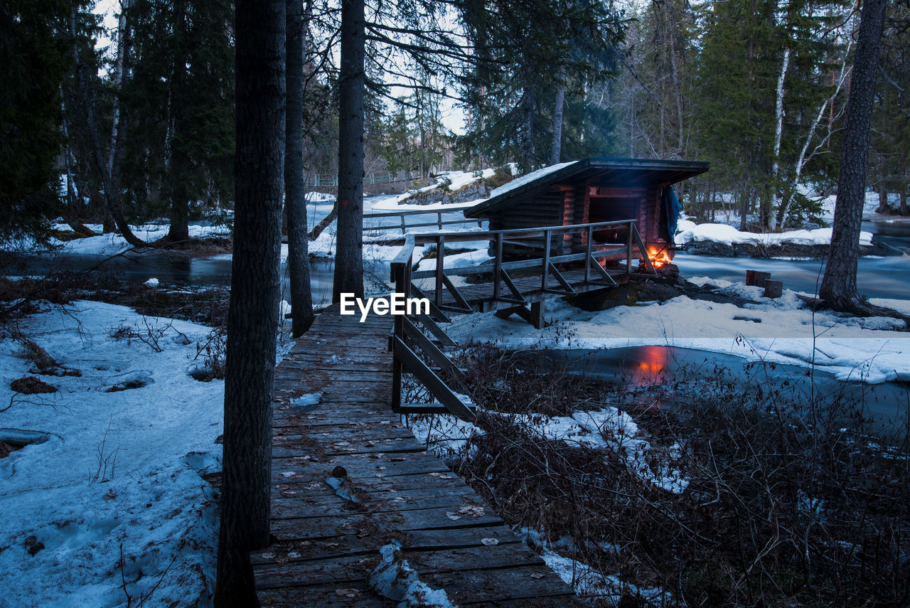 Wooden structure on snow covered land in forest