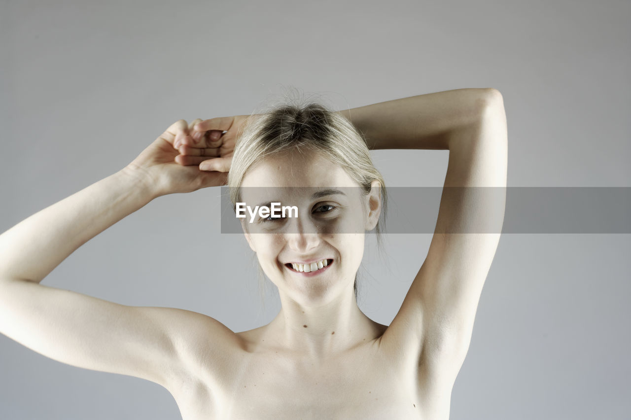 Portrait of a smiling young woman against gray background