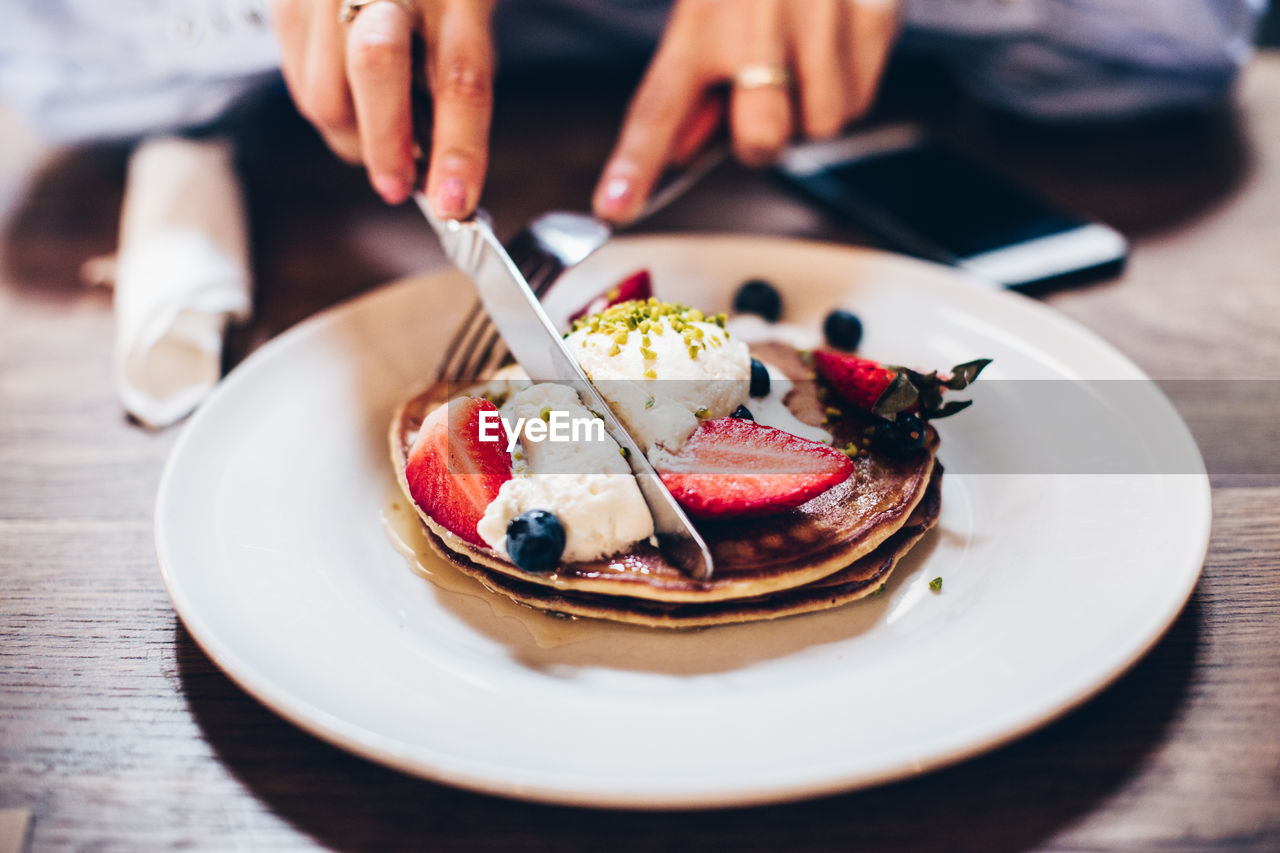 Close-up of hands eating pancakes