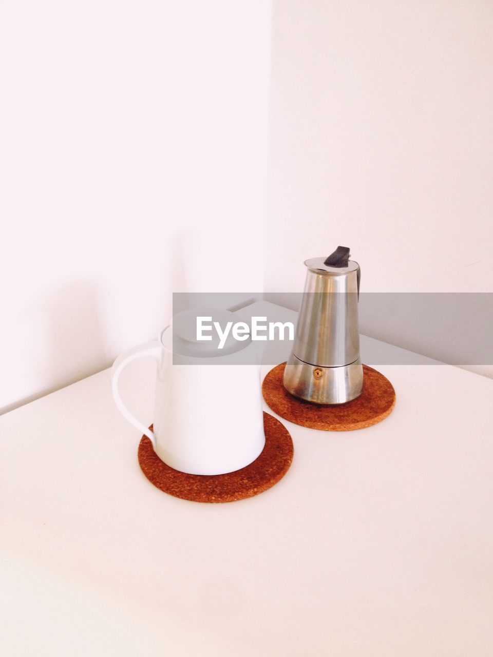 High angle view of coffee kettles on table against white wall