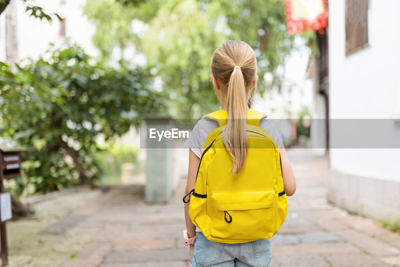 Schoolgirl back to school after summer vacations. happy child smiling early morning outdoor.