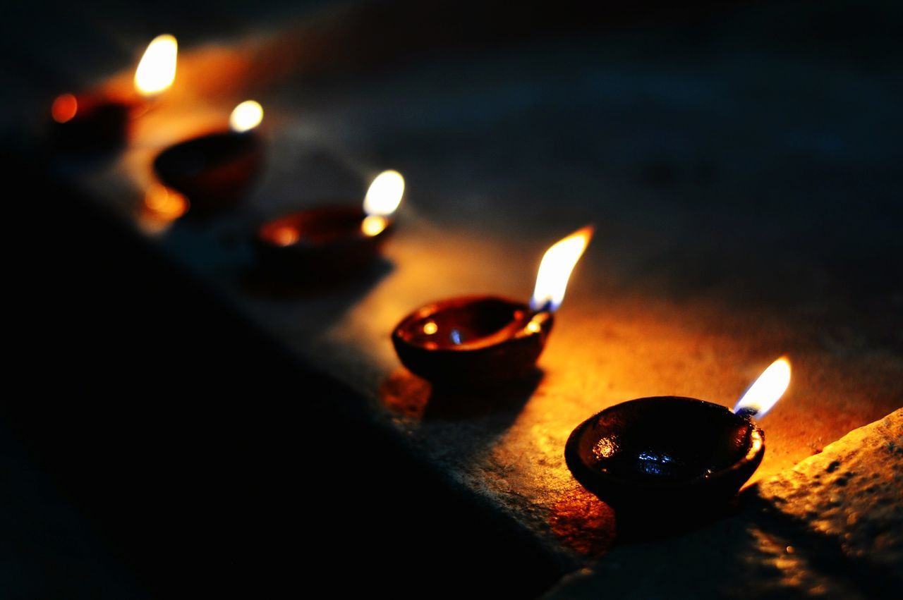 Close-up of illuminated diyas on retaining wall