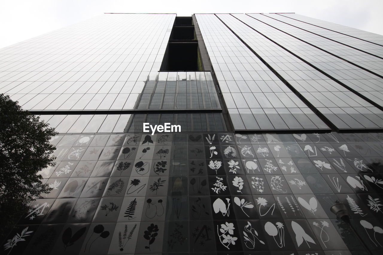 LOW ANGLE VIEW OF MODERN GLASS BUILDING IN CITY