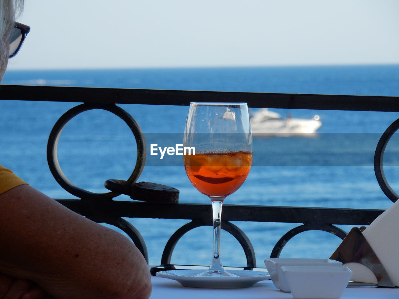 CLOSE-UP OF WINE GLASS AGAINST SEA