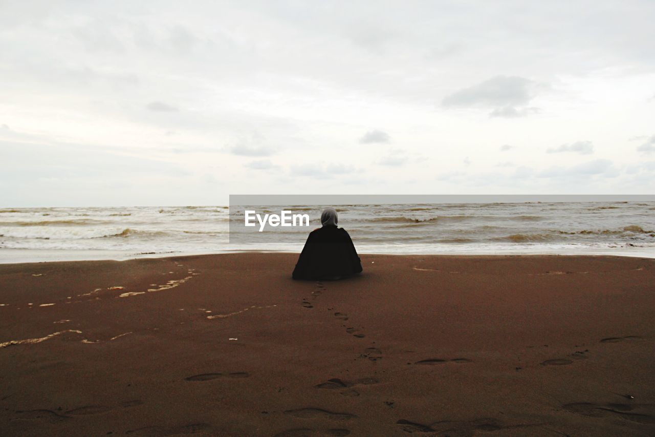 Rear view of woman relaxing on beach