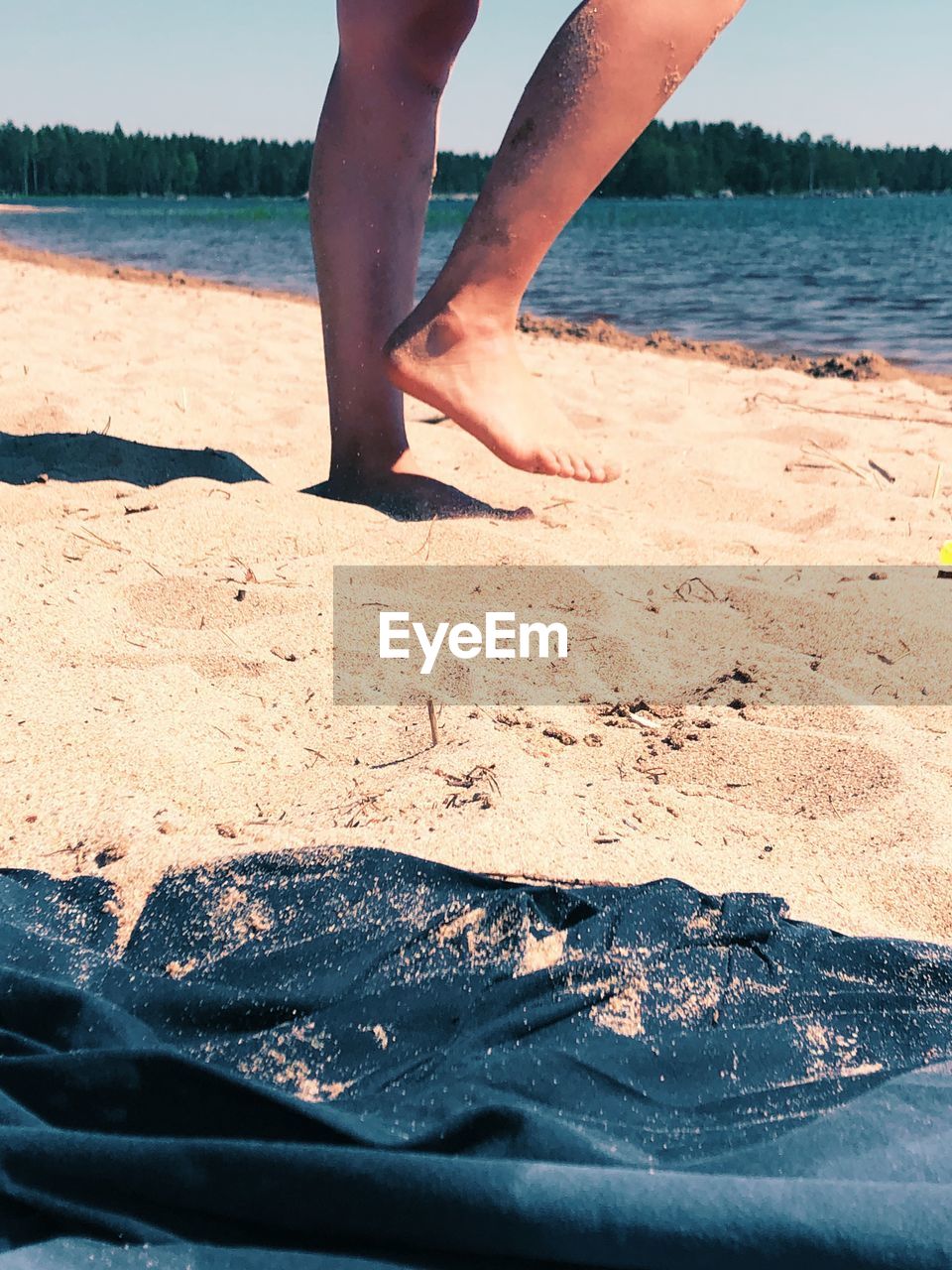 LOW SECTION OF MAN STANDING ON SHORE