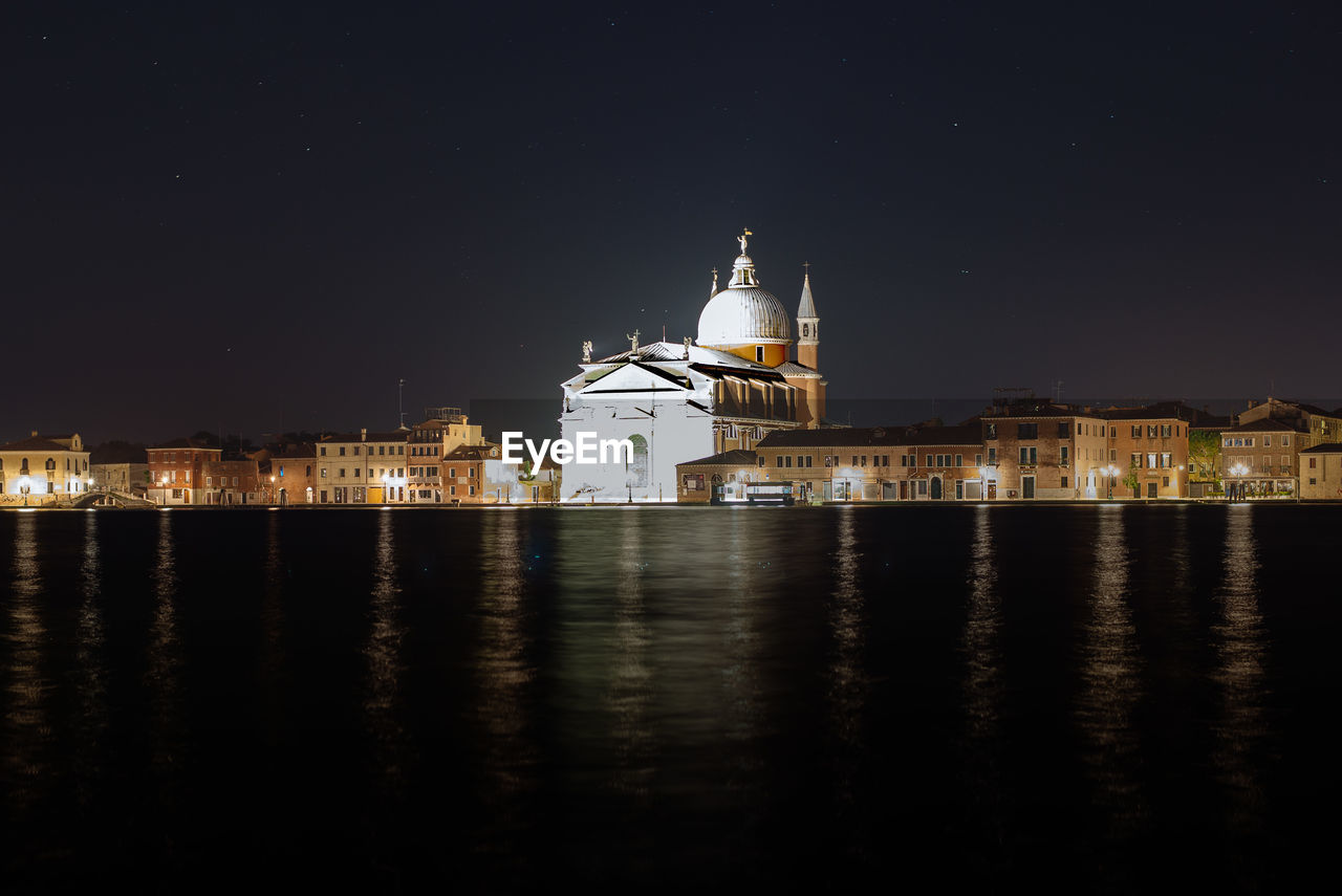 Exterior of illuminated il redentore by canal against clear sky at night