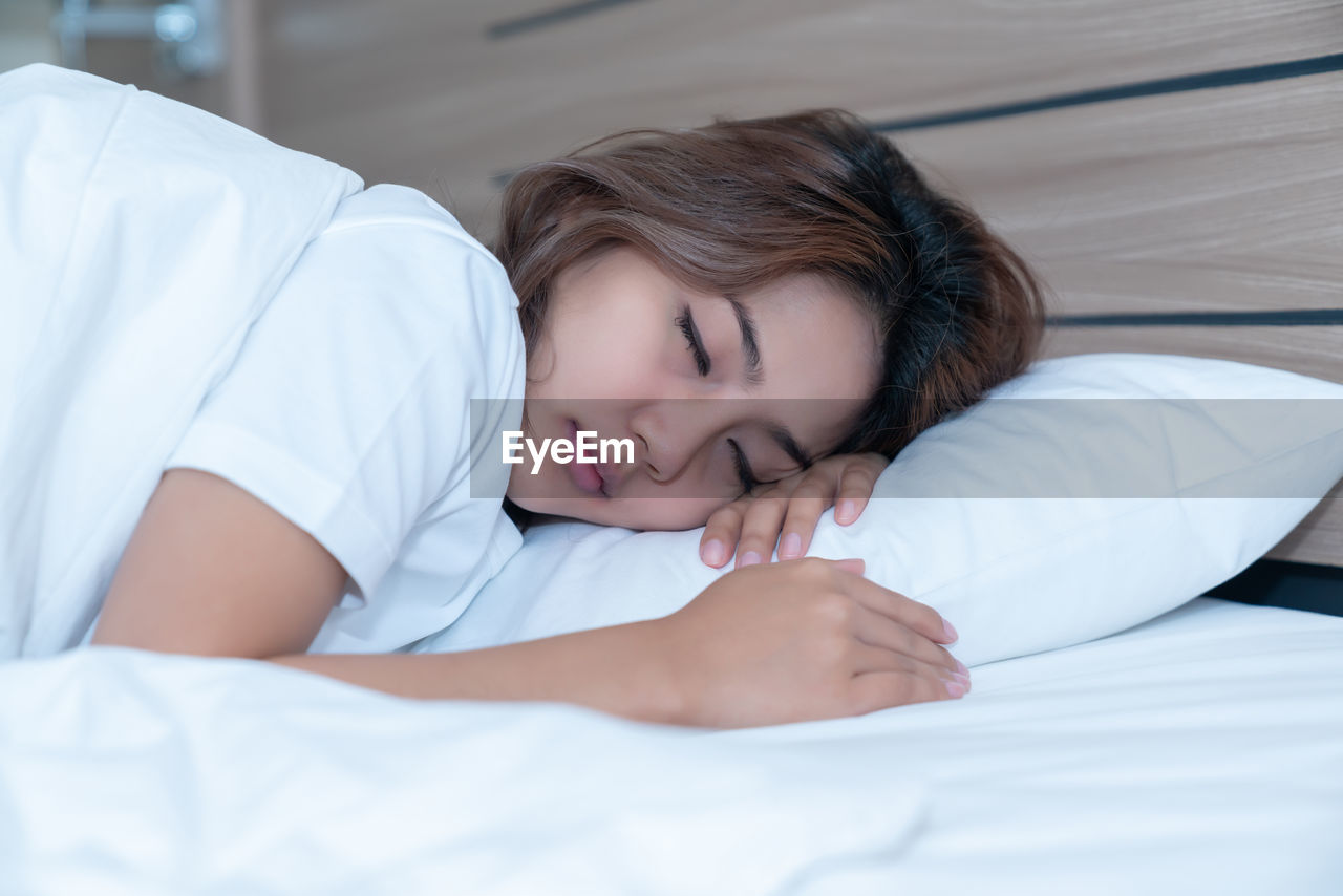 MIDSECTION OF WOMAN SLEEPING IN BED