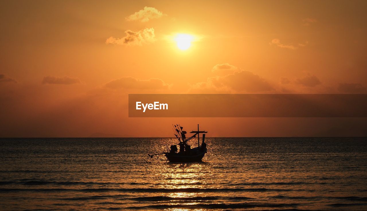 Silhouette boat sailing in sea against sky during sunset