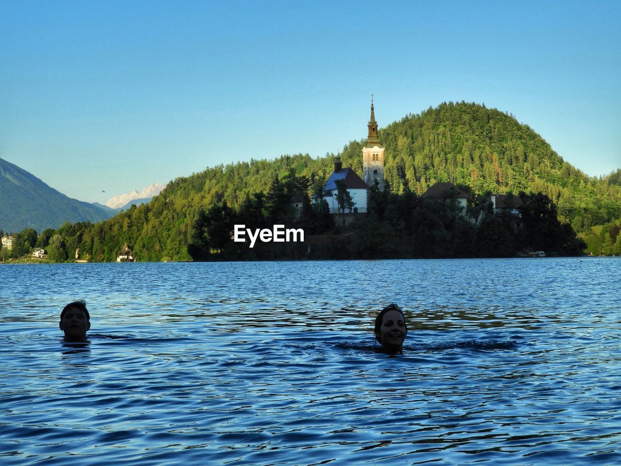 DUCKS SWIMMING ON LAKE AGAINST CLEAR BLUE SKY