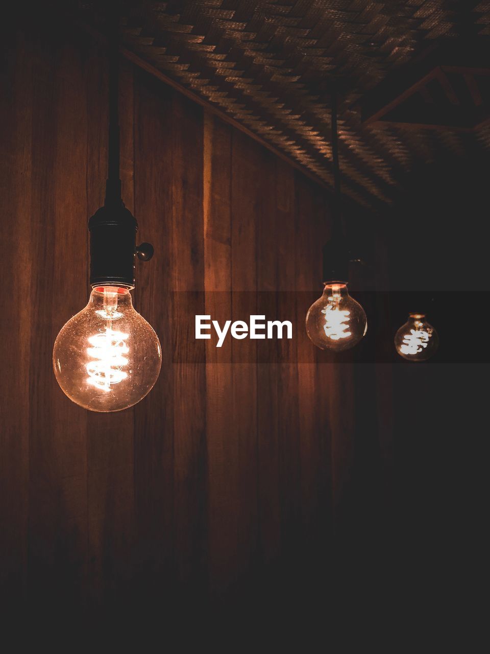 LOW ANGLE VIEW OF ILLUMINATED LIGHT BULB HANGING ON CEILING