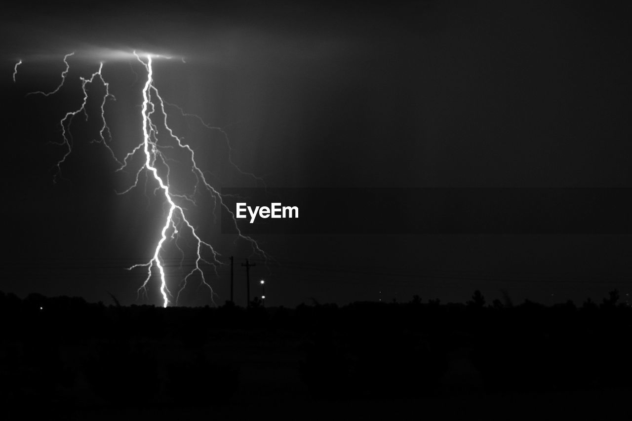 Lightning over land against sky at night