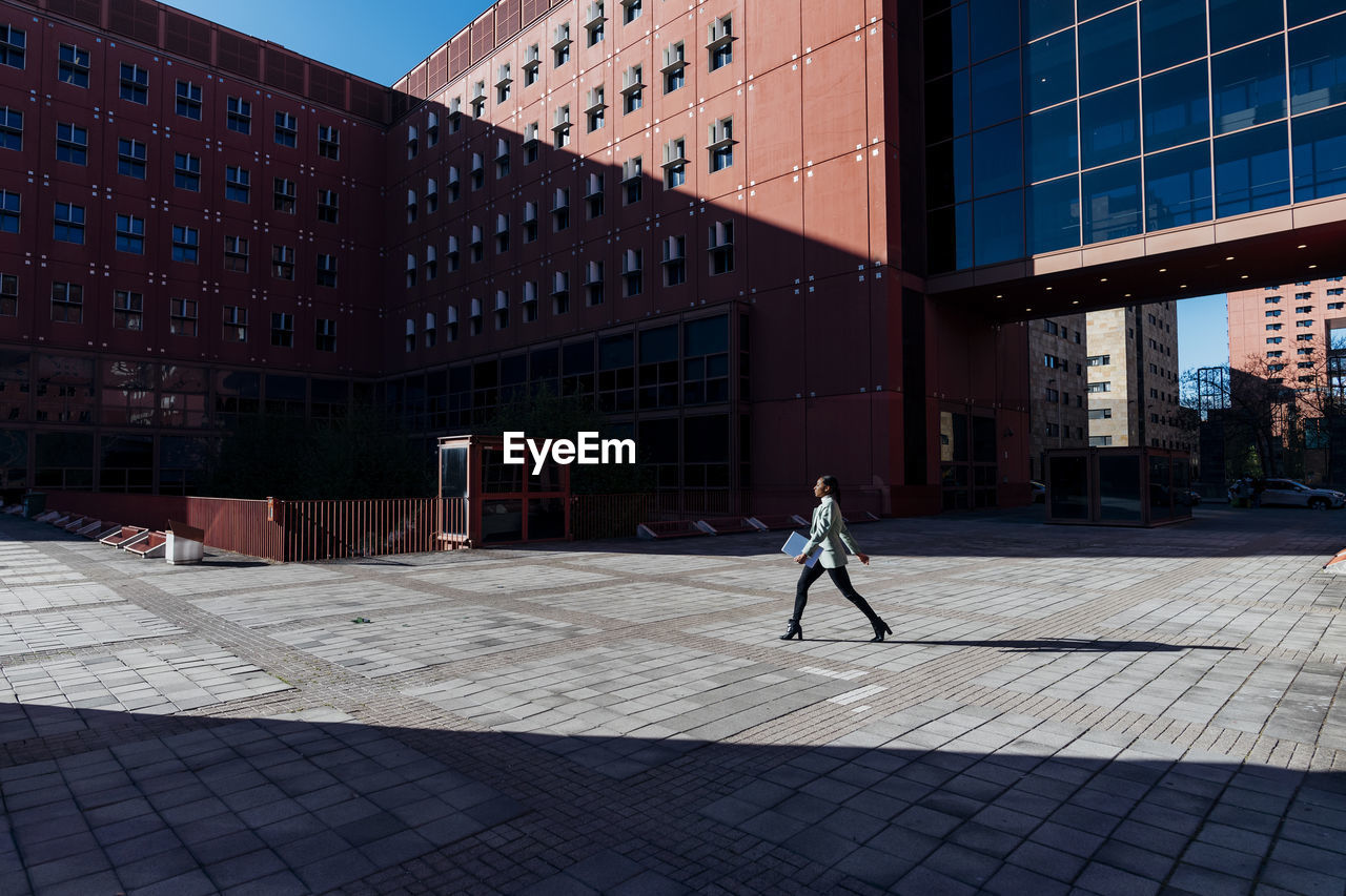 Businesswoman with laptop walking in office campus