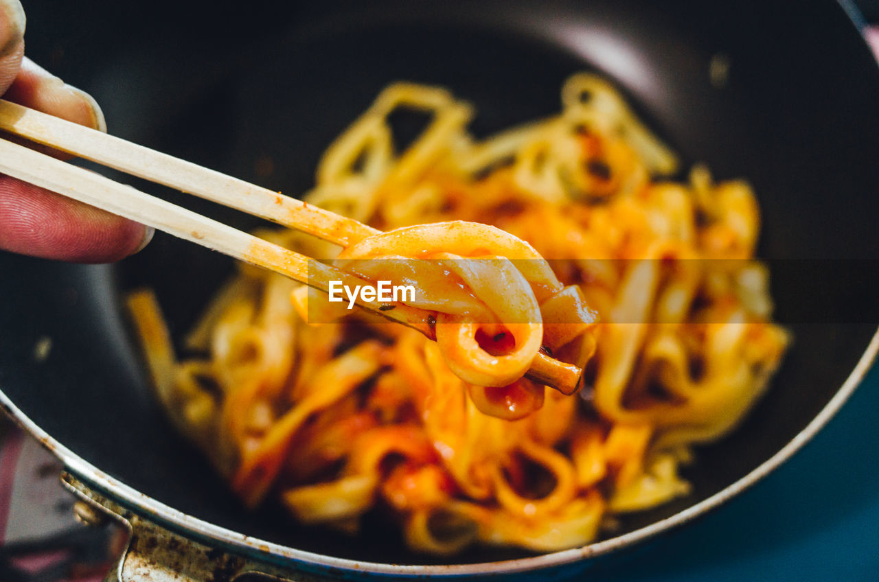 Cropped hand having pasta on table