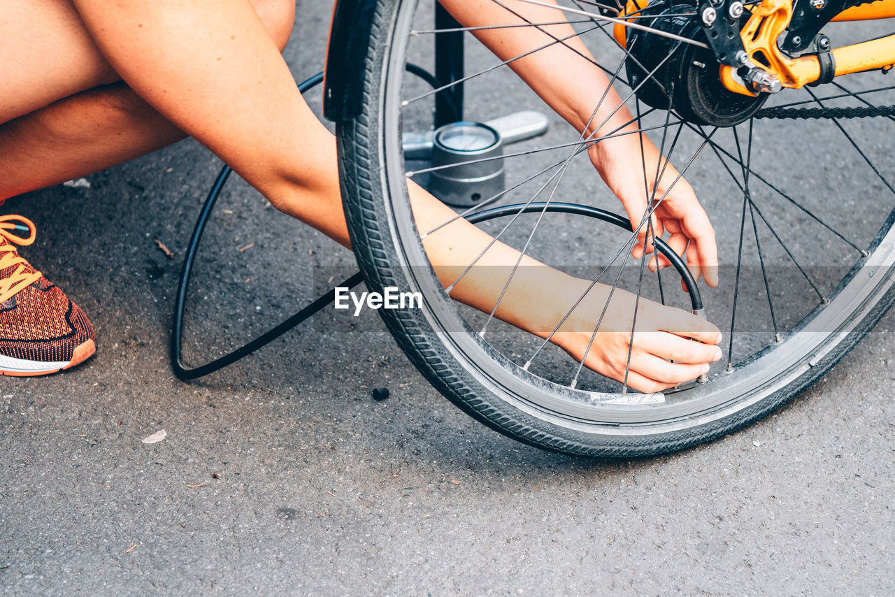 Cropped image of man pumping bicycle tire on street