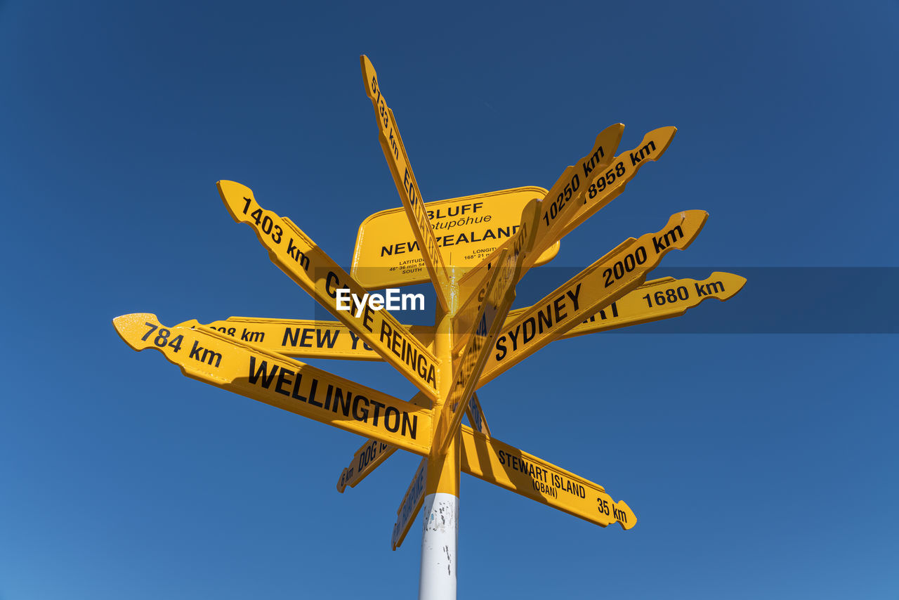 Low angle view of information sign against clear blue sky