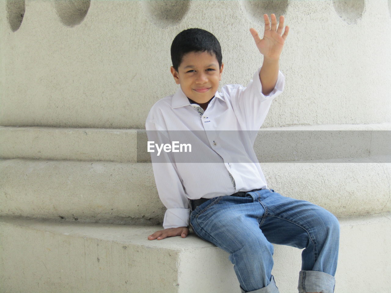 Portrait of boy sitting against while wall