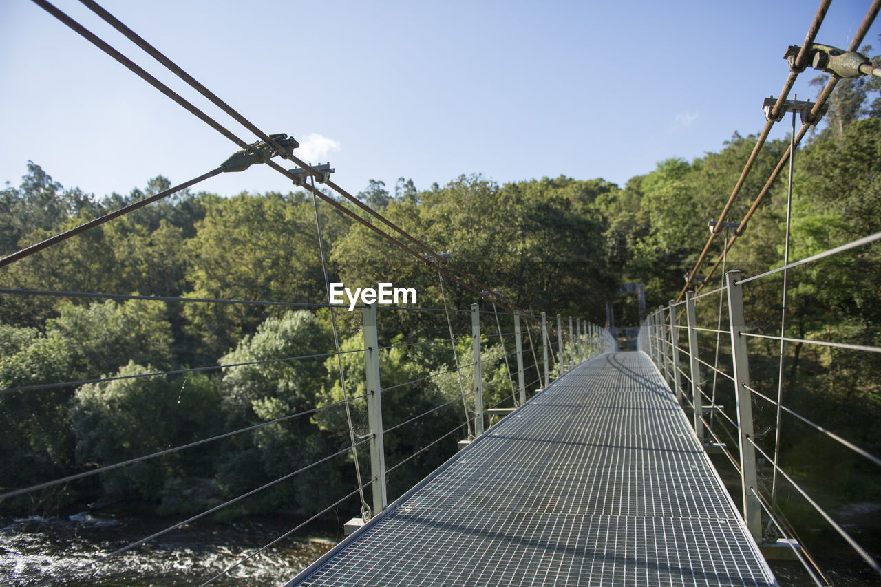 Footbridge amidst trees against clear sky