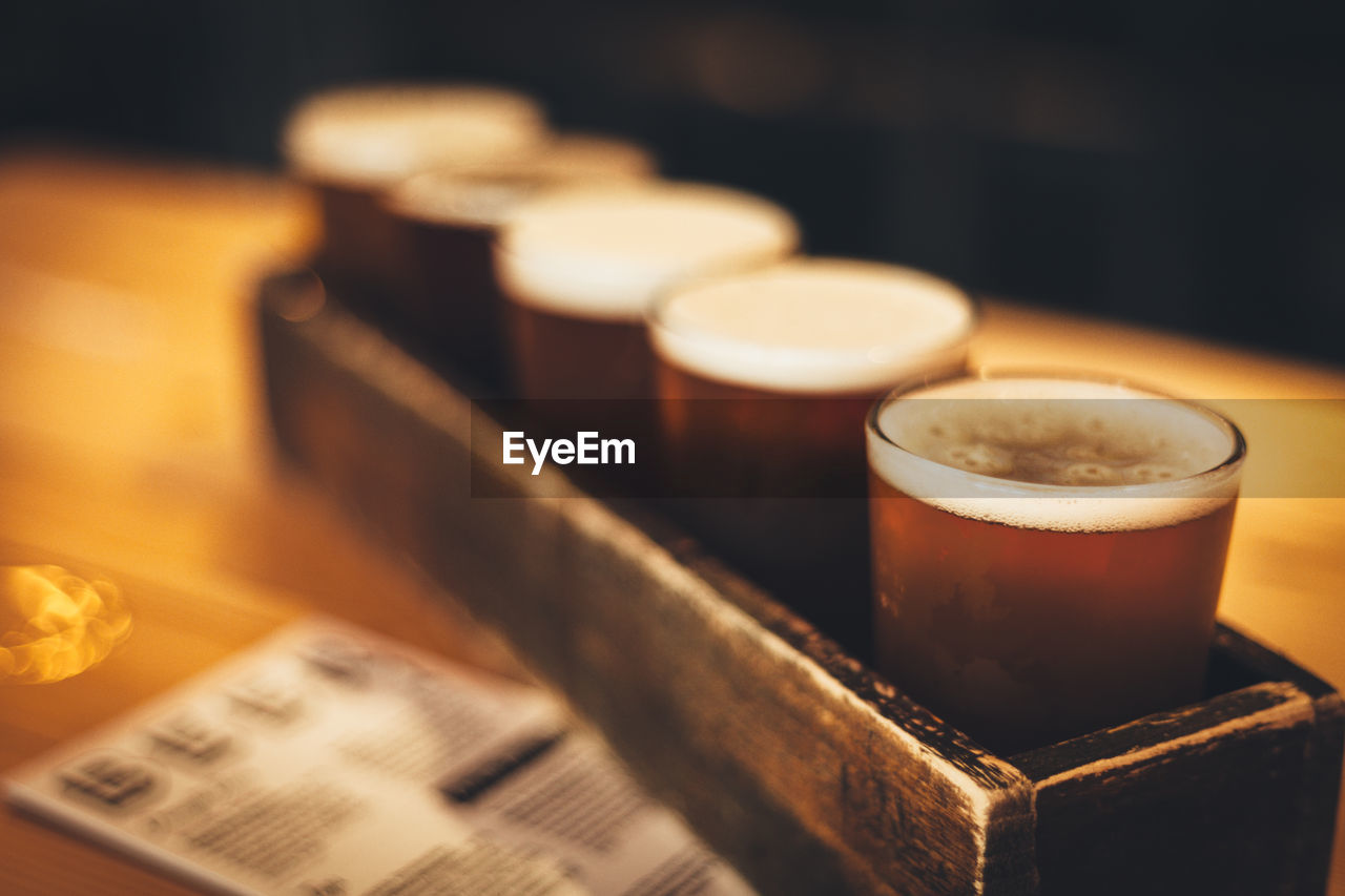 Beer glasses in wooden container on table at bar