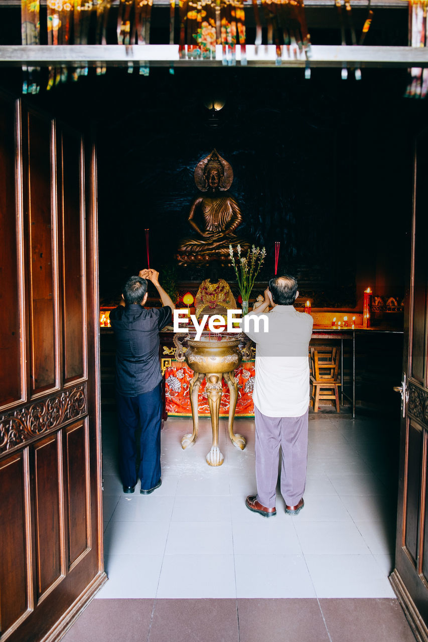 Rear view of men praying at temple