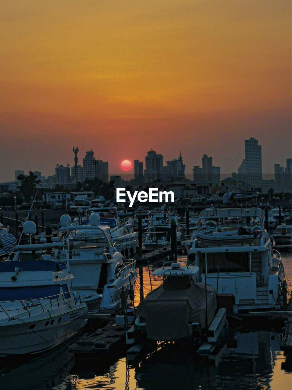High angle view over marina docks as sun sets between the high rise buildings of kuwait city 