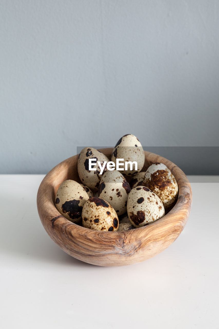 Speckled quail eggs in a rustic wooden bowl