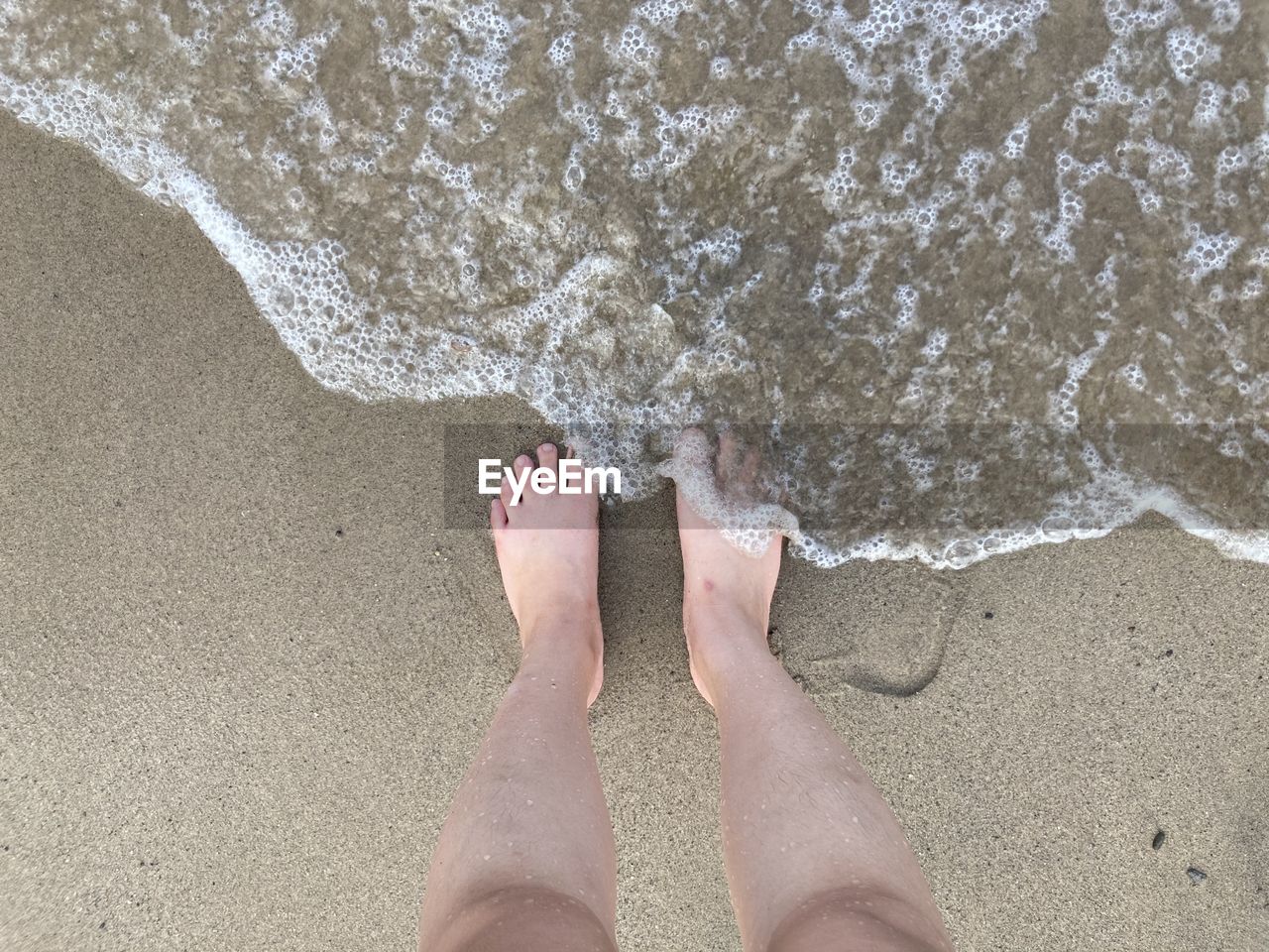 LOW SECTION OF PERSON LEGS ON SAND