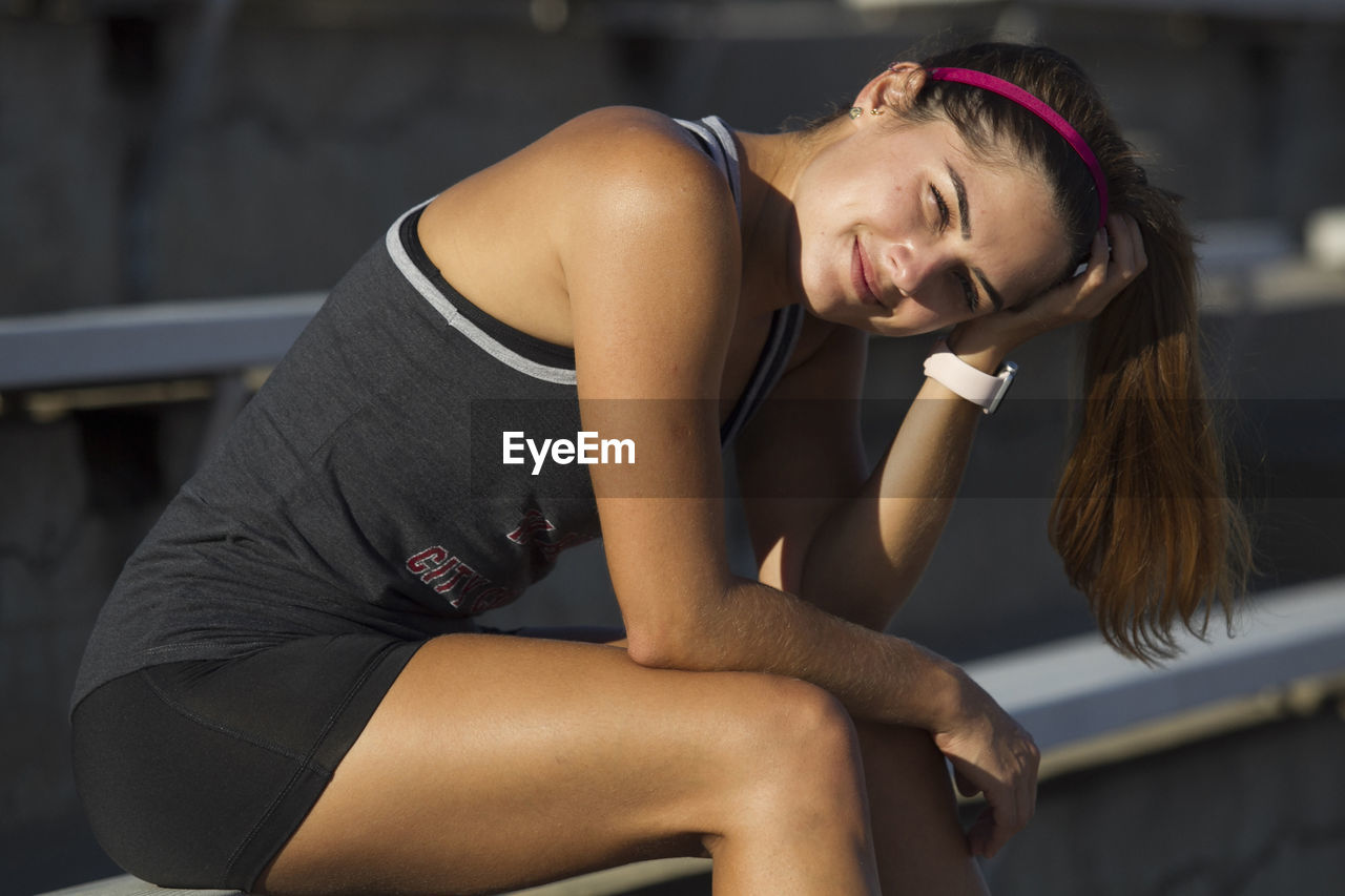 Portrait of confident woman wearing sports clothing while sitting outdoors