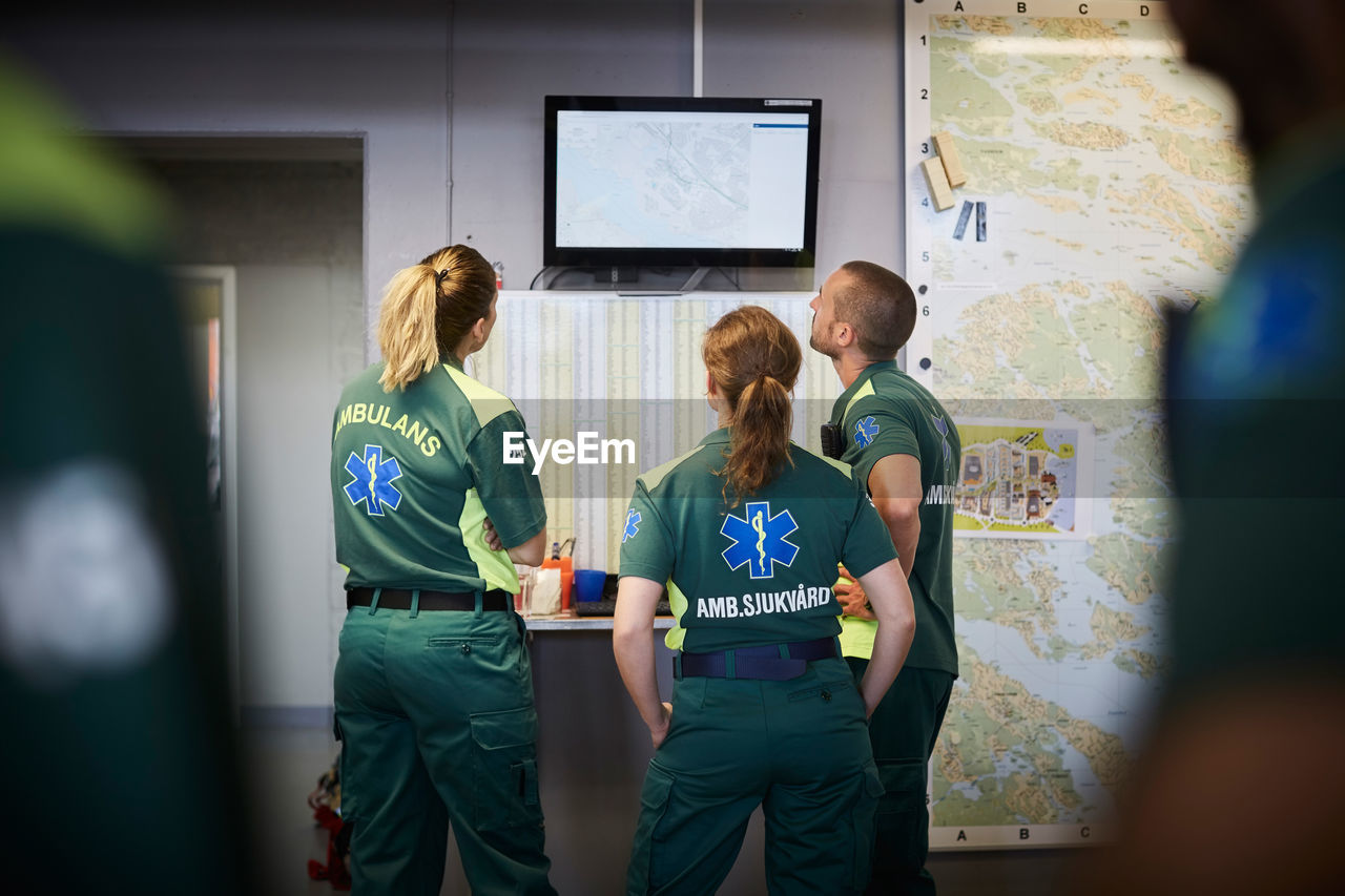 Paramedics discussing while looking at screen in hospital