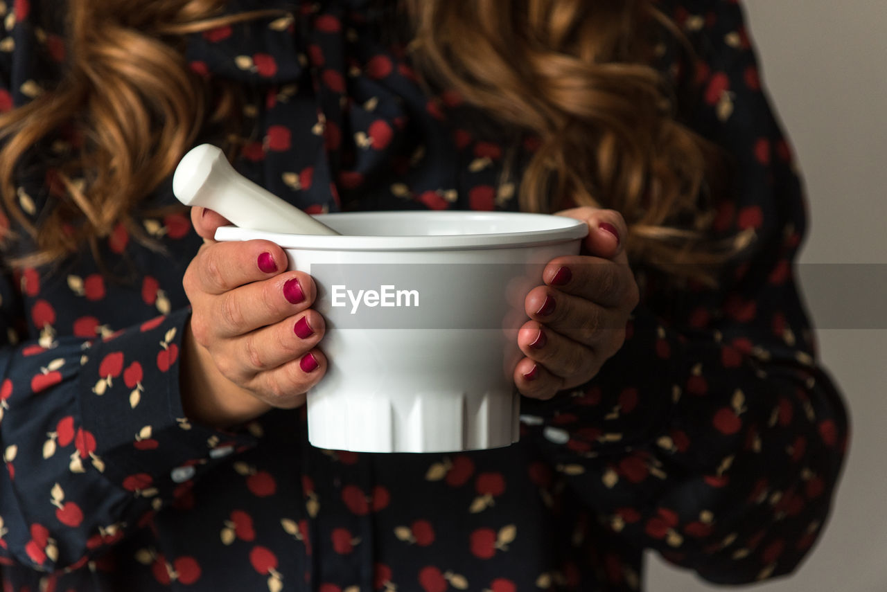 Midsection of woman holding white mortar and pestle