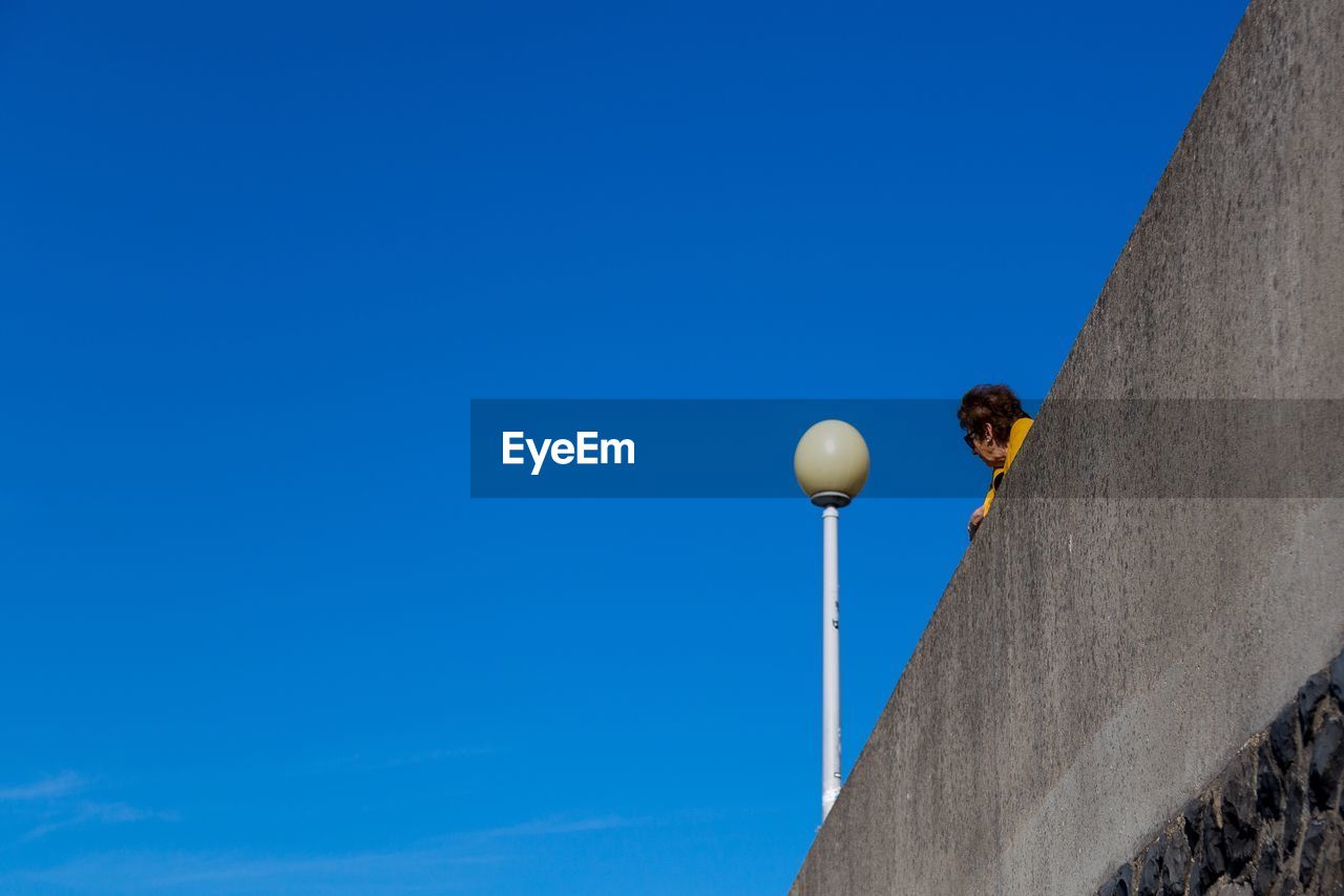 LOW ANGLE VIEW OF STREET LIGHTS AGAINST BLUE SKY